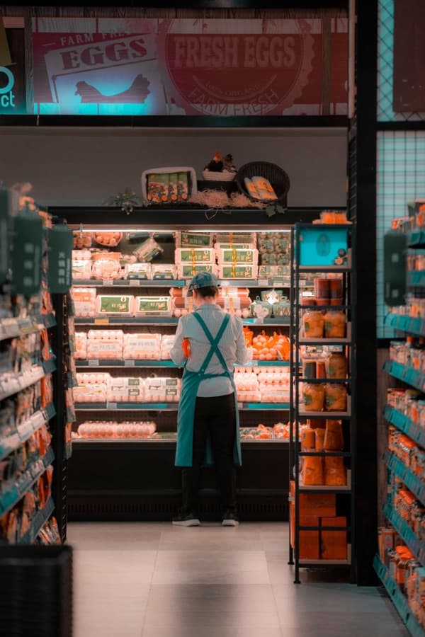 Empleada repone productos refrigerados en un supermercado